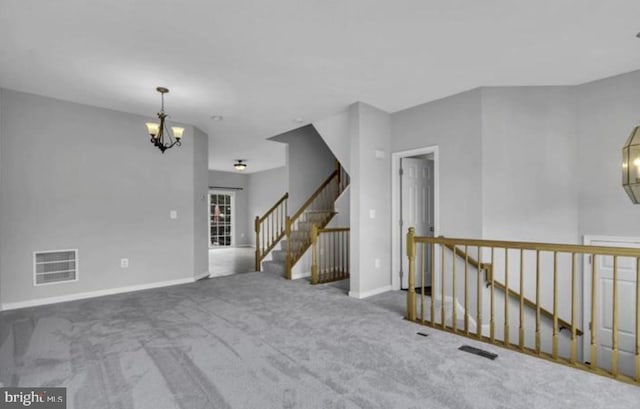 spare room featuring a chandelier, carpet, and baseboards