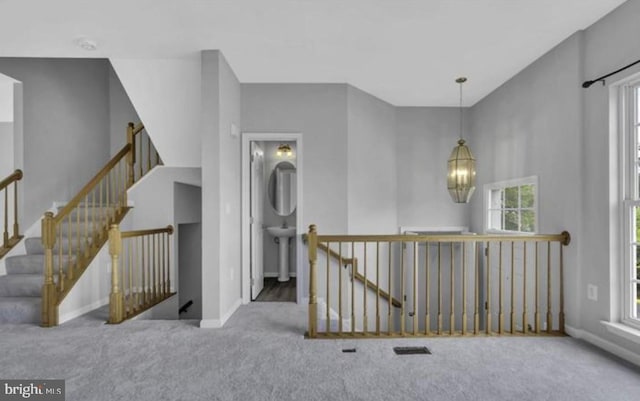 hallway featuring an upstairs landing, carpet floors, baseboards, and a chandelier