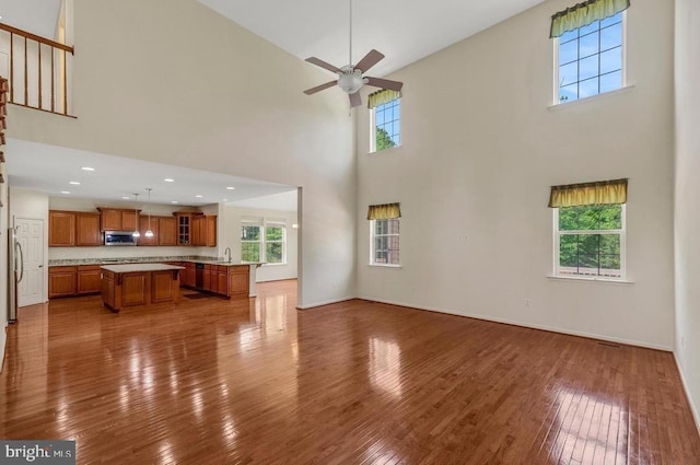 18776 Pier Trail Dr, Triangle, VA 22172 - unfurnished living room featuring a towering ceiling, dark wood finished floors, ceiling fan, a sink, and baseboards