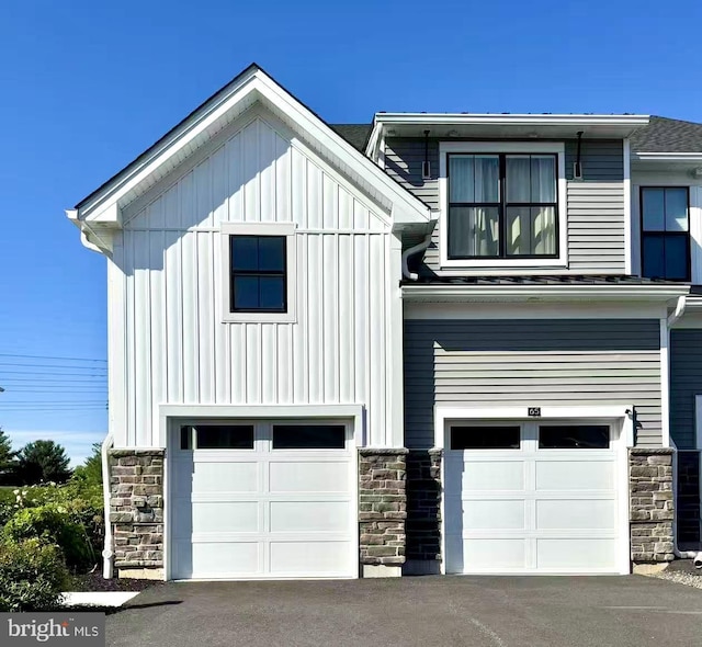 65 Tamarack Cir, Eagleville, PA 19403 - view of front of property featuring a garage, stone siding, board and batten siding, and asphalt driveway