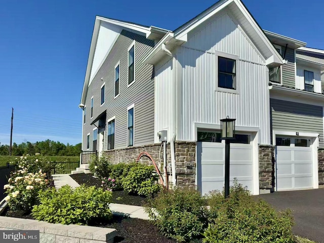 65 Tamarack Cir, Eagleville, PA 19403 - view of home's exterior with an attached garage, stone siding, board and batten siding, and driveway