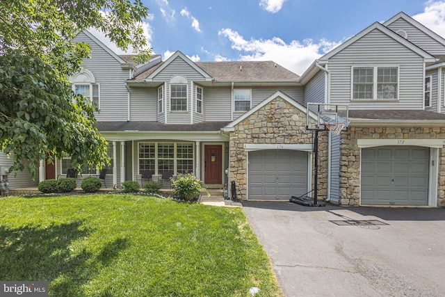 townhome / multi-family property featuring driveway, a front yard, stone siding, and a shingled roof