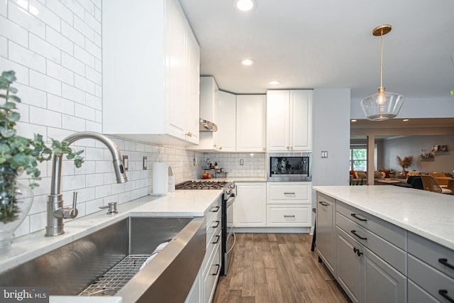 kitchen featuring stainless steel appliances, a sink, gray cabinetry, dark wood-style floors, and white cabinetry