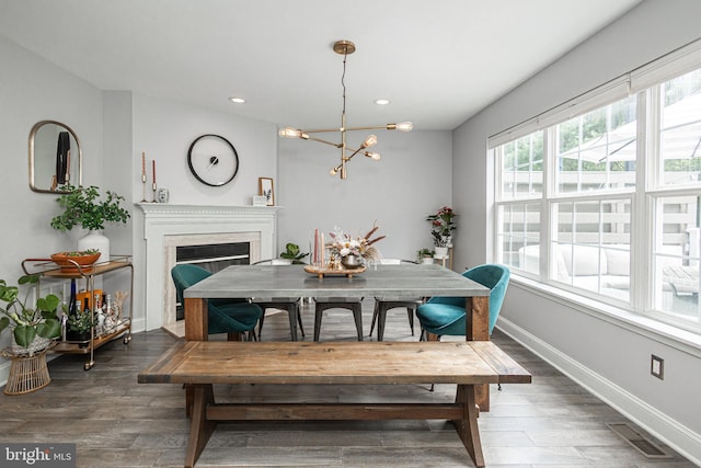 dining area featuring a chandelier, a glass covered fireplace, baseboards, wood finished floors, and recessed lighting