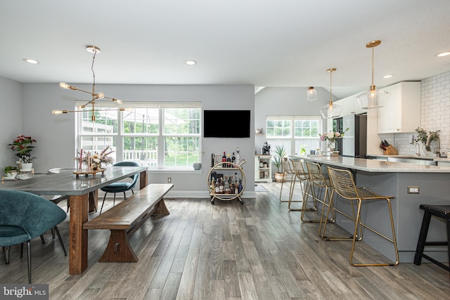 kitchen featuring white cabinets, healthy amount of natural light, dark wood finished floors, a kitchen bar, and recessed lighting