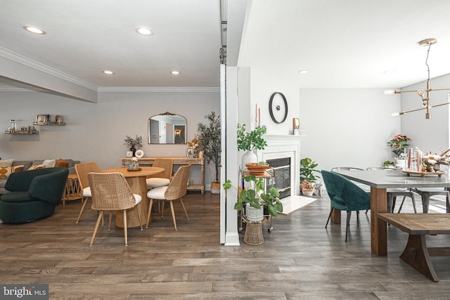 dining space featuring crown molding, a fireplace with flush hearth, wood finished floors, recessed lighting, and a chandelier