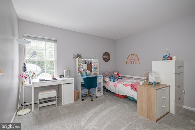 bedroom with an office area, carpet floors, and baseboards
