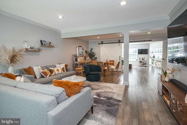 living area featuring a barn door, dark wood finished floors, crown molding, and recessed lighting