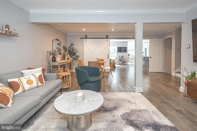 living room with wood finished floors, a barn door, ornamental molding, baseboards, and recessed lighting