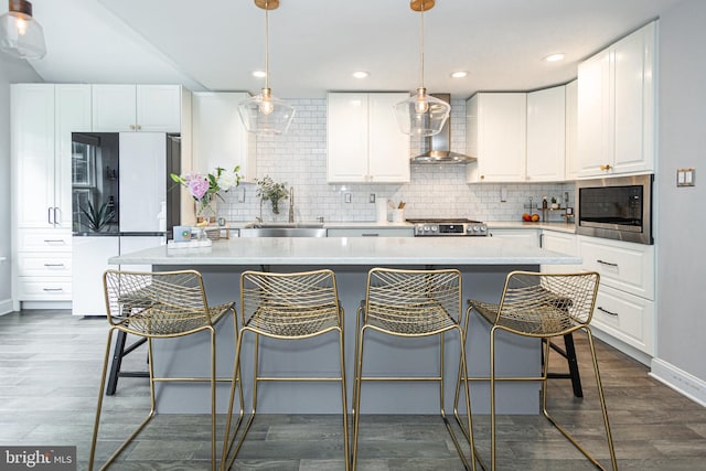 kitchen featuring a sink, built in microwave, wall chimney exhaust hood, freestanding refrigerator, and tasteful backsplash
