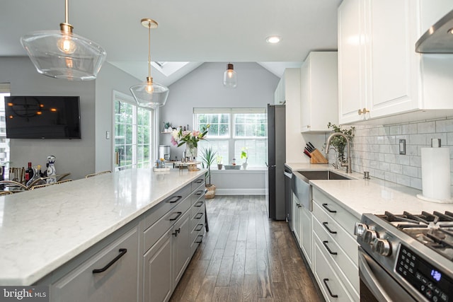 kitchen with under cabinet range hood, a sink, dark wood-style floors, light stone counters, and vaulted ceiling