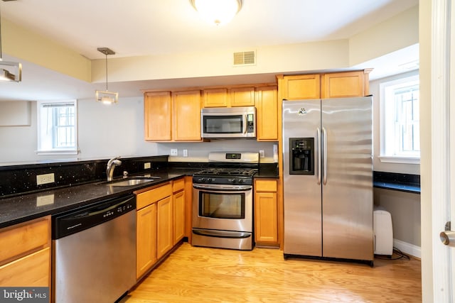 2510 Ontario Rd NW Unit 1, Washington, DC 20009 - kitchen featuring stainless steel appliances, a sink, light wood-type flooring, dark stone counters, and decorative light fixtures