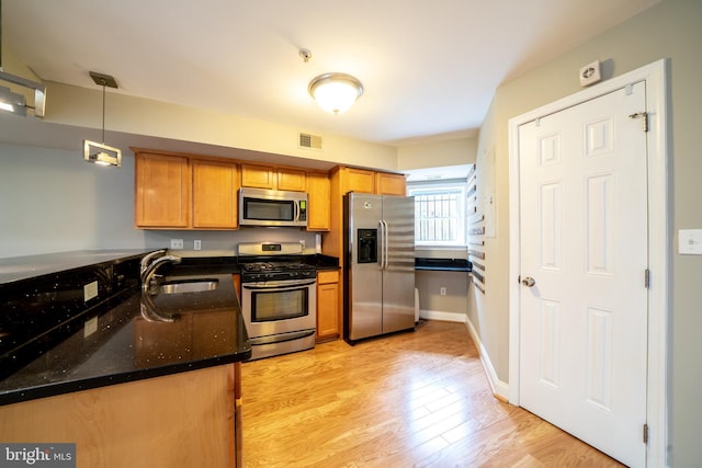 2510 Ontario Rd NW Unit 1, Washington, DC 20009 - kitchen featuring stainless steel appliances, a sink, light wood-style flooring, dark stone countertops, and pendant lighting