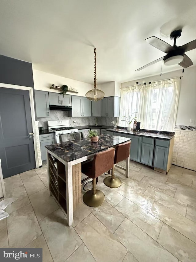 3100 Fanshawe St, Philadelphia, PA 19149 - kitchen featuring white gas range oven, gray cabinetry, a sink, dark countertops, and a kitchen island