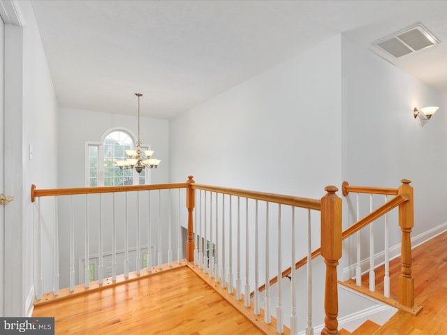 2411 Windwood Dr, Winchester, VA 22601 - corridor with wood finished floors, a chandelier, an upstairs landing, and baseboards