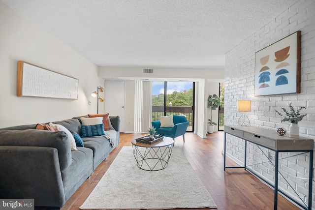 5300 Holmes Run Pkwy Unit 403, Alexandria, VA 22304 - living room with a textured ceiling, wood finished floors, and brick wall