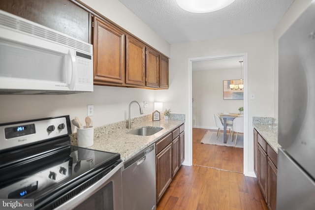 5300 Holmes Run Pkwy Unit 403, Alexandria, VA 22304 - kitchen with stainless steel appliances, a sink, dark wood-style floors, brown cabinetry, and light stone counters