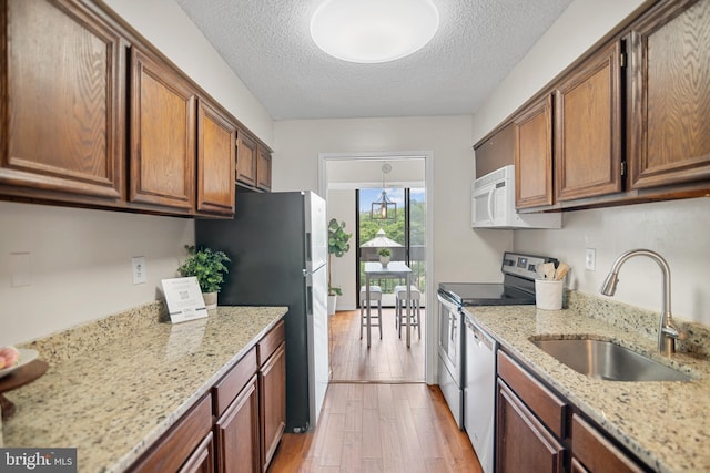 5300 Holmes Run Pkwy Unit 403, Alexandria, VA 22304 - kitchen with a sink, stainless steel appliances, light wood-type flooring, a textured ceiling, and brown cabinetry