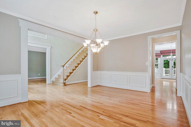 5257 Ferry Branch Ln, Lothian, MD 20711 - unfurnished dining area featuring a chandelier, light wood-style floors, stairs, a wainscoted wall, and a decorative wall