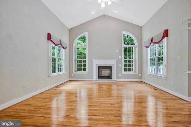 5257 Ferry Branch Ln, Lothian, MD 20711 - unfurnished living room featuring plenty of natural light, wood finished floors, a ceiling fan, a glass covered fireplace, and vaulted ceiling