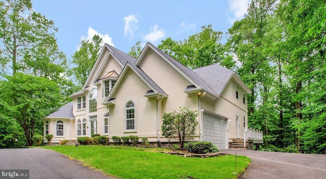 5257 Ferry Branch Ln, Lothian, MD 20711 - view of front of property with driveway, stucco siding, a front yard, an attached garage, and roof with shingles