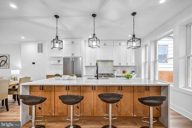 kitchen with freestanding refrigerator, backsplash, a sink, wood finished floors, and recessed lighting