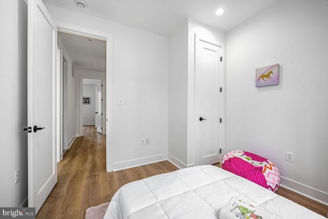 bedroom with wood finished floors, baseboards, recessed lighting, and a closet