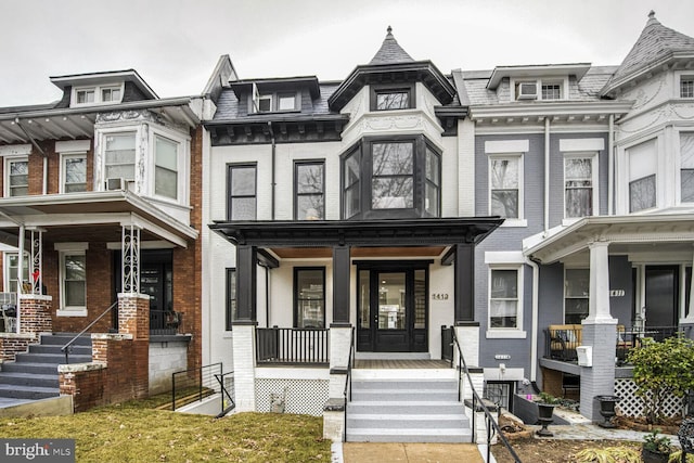 townhome / multi-family property with covered porch and brick siding