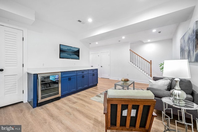living area featuring wine cooler, stairs, light wood-style floors, recessed lighting, and a bar