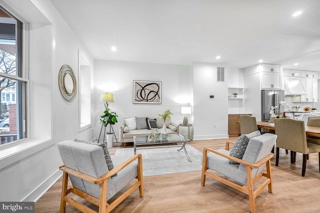 living room featuring light wood-style flooring, baseboards, and recessed lighting