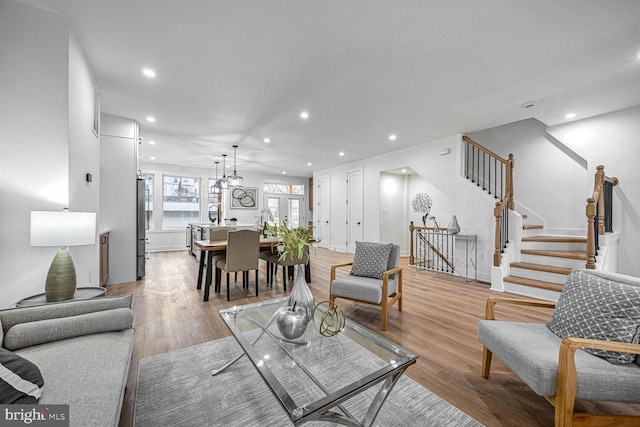 living area with recessed lighting, wood finished floors, stairway, and a chandelier