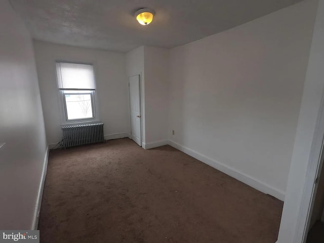 carpeted spare room featuring radiator heating unit and baseboards