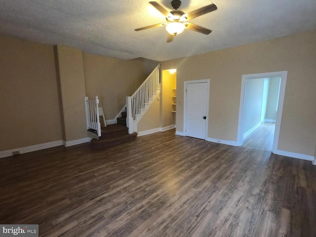 unfurnished living room featuring dark wood-style floors, a ceiling fan, stairs, and baseboards