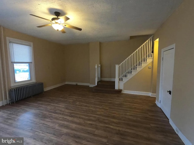 unfurnished living room with radiator heating unit, a ceiling fan, dark wood-style floors, stairs, and a textured ceiling