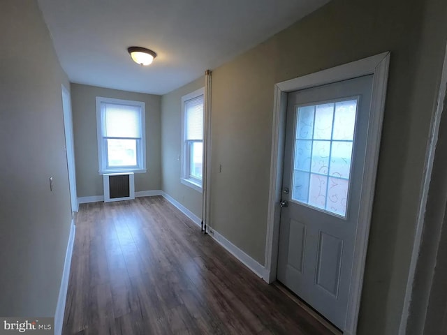 doorway to outside with dark wood finished floors, baseboards, and radiator heating unit