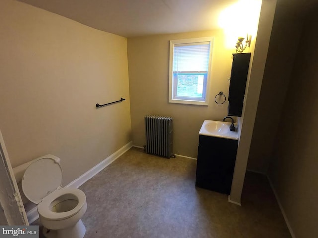 half bathroom featuring radiator heating unit, vanity, toilet, and baseboards