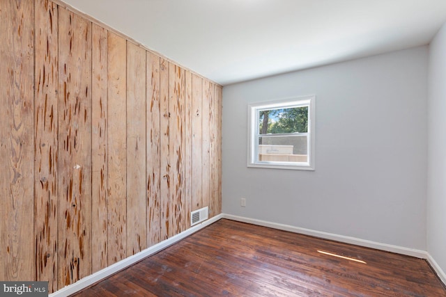 empty room featuring wood finished floors, baseboards, and wooden walls