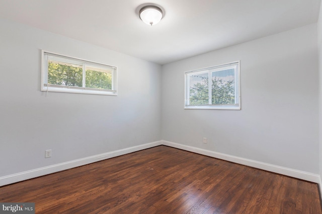 unfurnished room with healthy amount of natural light, dark wood-style flooring, and baseboards
