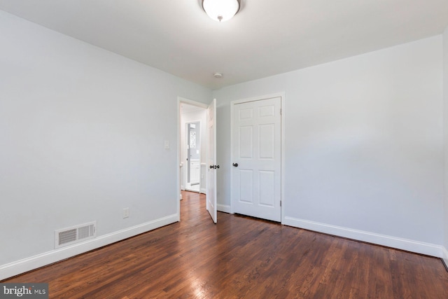 unfurnished room with baseboards, dark wood finished floors, and a smoke detector