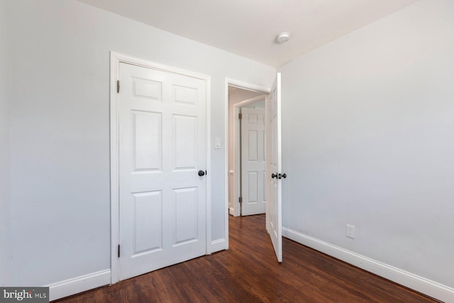 unfurnished bedroom featuring baseboards and dark wood finished floors