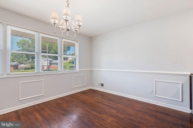 spare room with a chandelier, baseboards, and dark wood finished floors