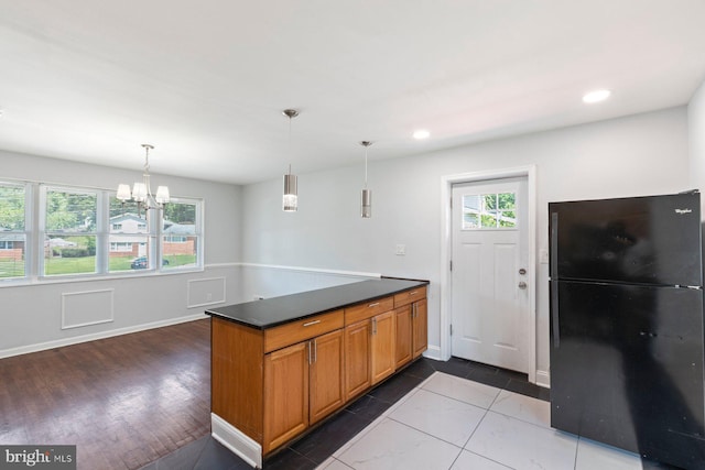 kitchen with freestanding refrigerator, dark countertops, brown cabinets, a chandelier, and baseboards