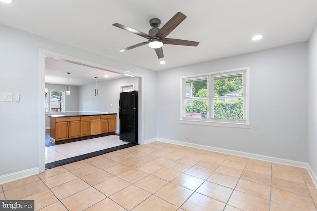 kitchen with freestanding refrigerator, a ceiling fan, recessed lighting, light tile patterned flooring, and brown cabinets