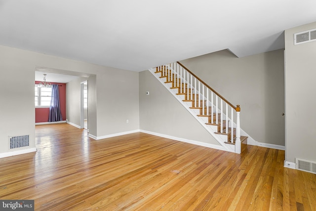1243 Maple Ave, Wilmington, DE 19805 - unfurnished living room with light wood-type flooring, stairs, a chandelier, and baseboards