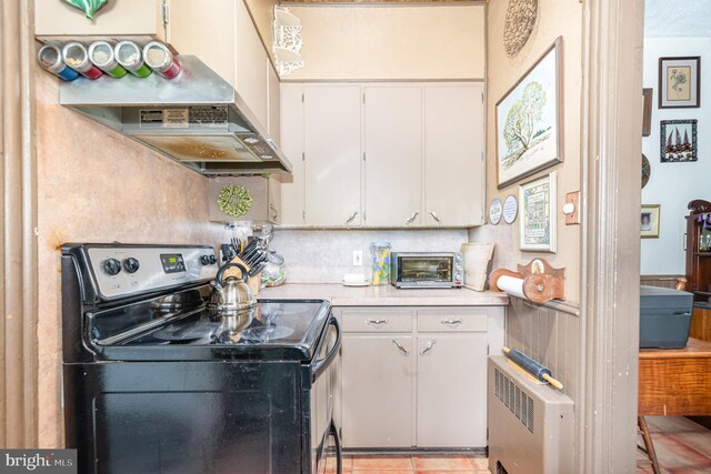 135 Lucknow Rd, Harrisburg, PA 17110 - kitchen with electric stove, radiator, light countertops, wall chimney range hood, and light tile patterned floors
