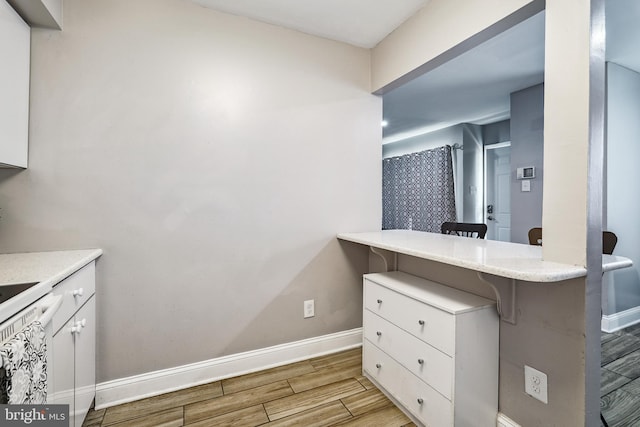 205 Highland Blvd, New Castle, DE 19720 - kitchen with baseboards, wood tiled floors, white cabinetry, and a kitchen bar