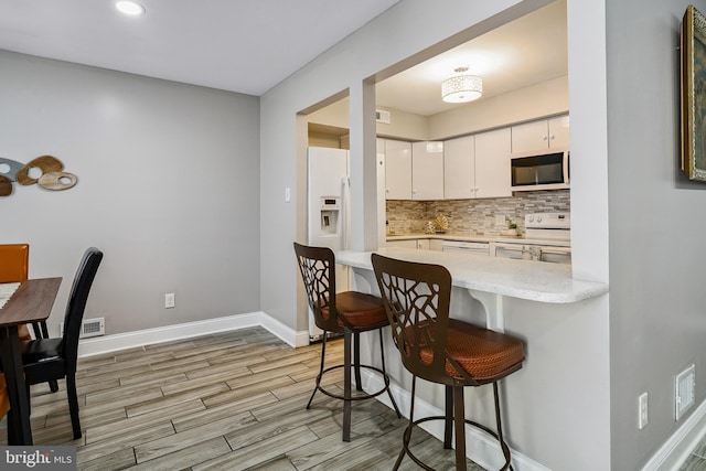 205 Highland Blvd, New Castle, DE 19720 - kitchen featuring white appliances, backsplash, white cabinets, a breakfast bar, and light countertops