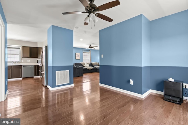 unfurnished living room featuring a ceiling fan, wood finished floors, and baseboards