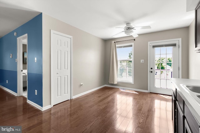 unfurnished dining area featuring ceiling fan, wood finished floors, and baseboards