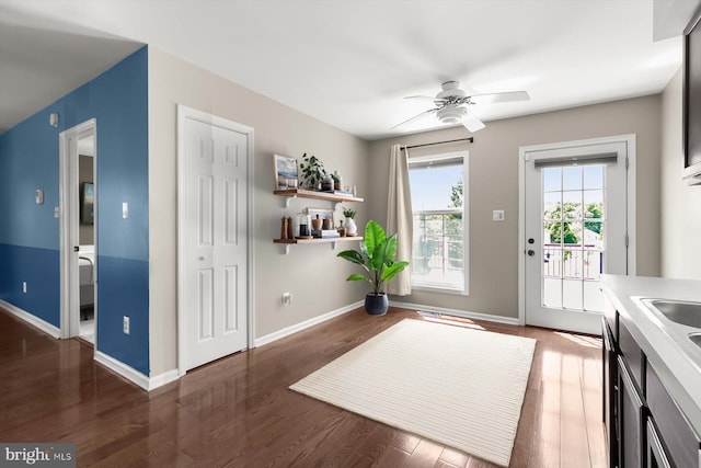 doorway featuring ceiling fan, wood finished floors, and baseboards